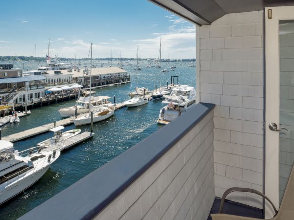 A balcony view overlooking a marina with several boats docked, under a clear blue sky.