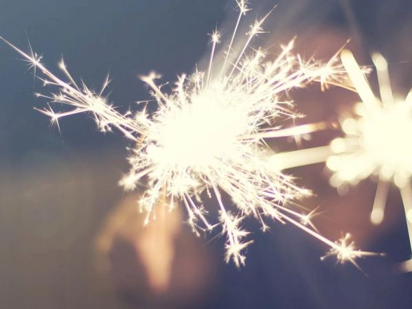 The image shows two bright sparklers burning against a dark background, creating a festive and vibrant display.
