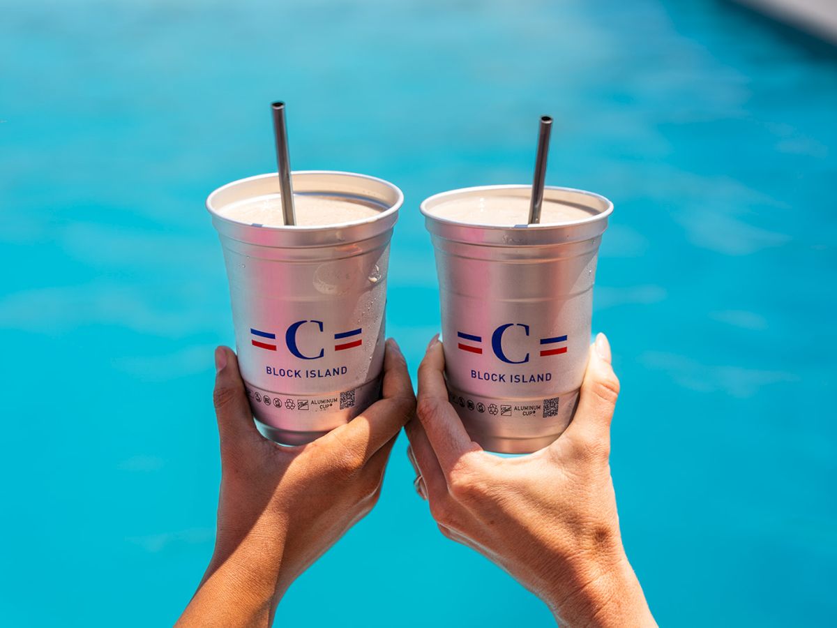 Two hands hold metal cups with straws by a pool, labeled "Block Island."