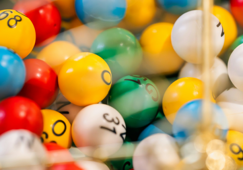 Colorful numbered balls in a claw-machine tray, blurred and shiny, with digits and symbols visible on several balls.