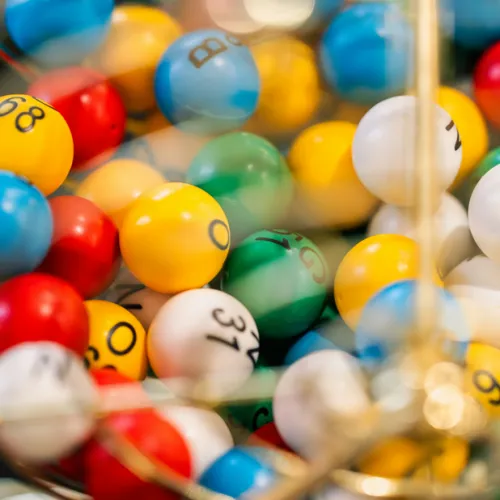 Colorful numbered balls in a claw-machine tray, blurred and shiny, with digits and symbols visible on several balls.